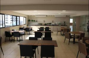 a restaurant with tables and chairs and a kitchen at Apart estiloso! in Feira de Santana