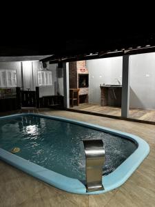 a swimming pool with a chair in a house at Casa Familiar da Mari in São Gabriel