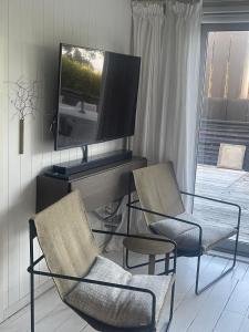 Una sala de estar con dos sillas y un televisor. en Little Oneroa Beach Bach, en Waiheke Island