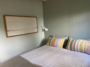 Un dormitorio con una cama y un cuadro en la pared. en Little Oneroa Beach Bach, en Waiheke Island
