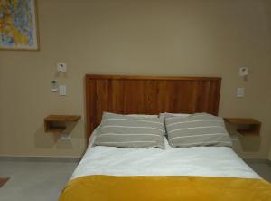 a bed with a wooden head board and two pillows at Parador de Chacras Suite in Ciudad Lujan de Cuyo