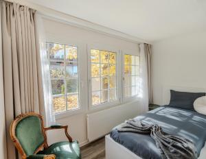 een slaapkamer met een bed, een stoel en ramen bij Mountain Residence in Kandersteg +59 foto's