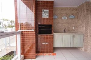 a kitchen with a brick wall and a sink at Apto em Bertioga a beira mar com varanda gourmet in Ilha Monte Pascoal