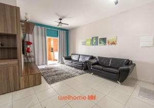 a living room with two leather couches and a tv at Apto em Bertioga a beira mar com varanda gourmet in Ilha Monte Pascoal