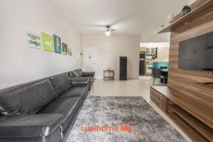 a living room with a black leather couch and a flat screen tv at Apto em Bertioga a beira mar com varanda gourmet in Ilha Monte Pascoal +61 photos