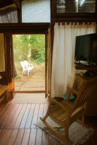 ラ・ルシラ・デル・マールにあるCabaña en El Pinar de La lucila del mar -de un piso-, El Pinar -6 personas-のテレビとポーチに椅子が置かれたリビングルーム