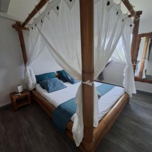 een slaapkamer met een hemelbed en witte gordijnen bij Oasis Grande Anse in Deshaies