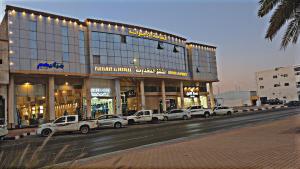 a large building with cars parked in front of it at فخامه الارجوانه للشقق المخدومة in Sakakah