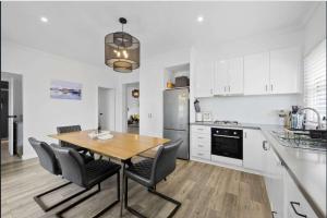 a white kitchen with a wooden table and chairs at Eureka We struck a golden home in Eureka
