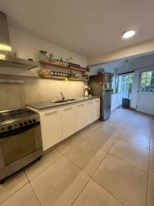 a large kitchen with white cabinets and a stove at Chalet en zona Güemes-SOLO FAMILIAS in Mar del Plata