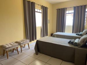 a bedroom with two beds and a chair and windows at Loft Central Orgânico in Passos