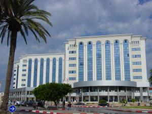 a large white building with a palm tree in front of it at Dream Appartement Monastir in Monastir