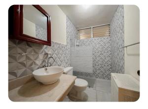 a bathroom with a sink and a toilet and a mirror at Hermoso apartamento en piantini Santo Domingo RD in La Julia
