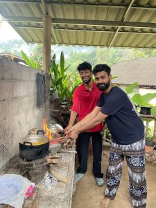 two men standing in front of a grill at Joyful Haven Home in Ban Ngiu Thao Mai