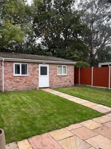 a brick house with a white door and a yard at Luxury Four Bedroom House in Rock Ferry