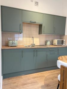 a kitchen with blue cabinets and a sink at Luxury Four Bedroom House in Rock Ferry