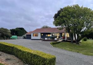 a house with a tree and a driveway at Rural Stay On City Doorstep in Palmerston North