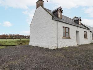 a white cottage on a gravel road at The Croft House in Muir of Ord