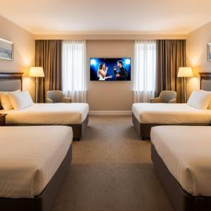 a hotel room with three beds and a flat screen tv at Boulevard Side Hotel in Baku