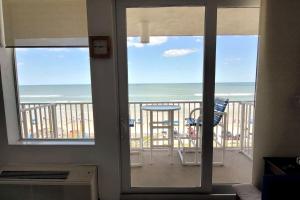 a room with a balcony with a view of the ocean at Direct Oceanfront 1BR Balcony King Bed Beach Access in Daytona Beach