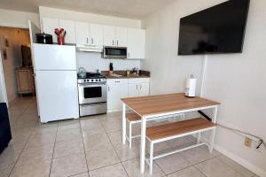 a kitchen with a white refrigerator and a table at Direct Oceanfront 1BR Balcony King Bed Beach Access in Daytona Beach