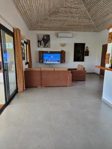 a living room with a couch and a flat screen tv at Villa d'évasion proche de la plage in Boukot Ouolof