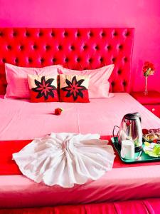 a pink bedroom with a large bed with a red headboard at White Palace airport hotel in Katunayake
