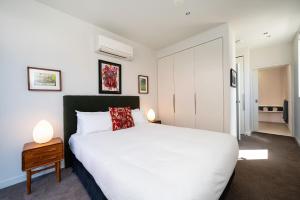 una camera da letto con un letto bianco e due lampade su un tavolo di Fitzroy 2BR Patio Parking & Pet-Friendly a Melbourne