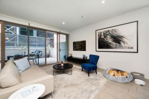 soggiorno con divano e cane sdraiato su una sedia di Fitzroy 2BR Patio Parking & Pet-Friendly a Melbourne