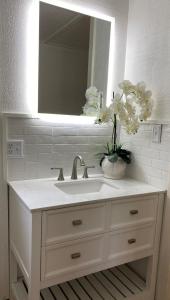 a white bathroom sink with a mirror and flowers on it at Red Roof Cabin - Suite 