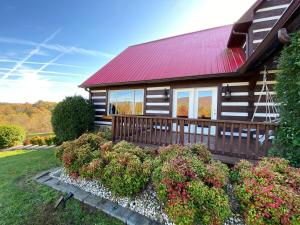 a wooden house with a red roof and some bushes at Red Roof Cabin - Suite 
