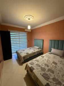 Un dormitorio con dos camas y una ventana. en Appartement Jihan, en Tánger