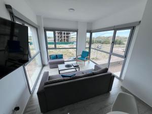 a living room with a couch and chairs and windows at Torres Al Mar in Monte Hermoso