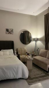 a bedroom with a bed and a couch and a mirror at استديو هادئ وأنيق بتصميم عصري in Al Kharj