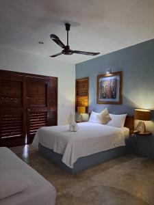 een slaapkamer met een groot bed met een plafondventilator bij Hotel Maria Maria in Bacalar