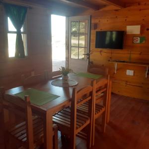 a dining room with a table and chairs and a television at Cabañas Batavi in Punta Del Diablo