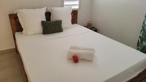 a white bed with white pillows and a stuffed animal on it at Villa indigo Gp in Vieux-Habitants