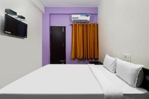 BelagulaHotel O MK Arcade的一间卧室配有一张床,另一间配有电视。