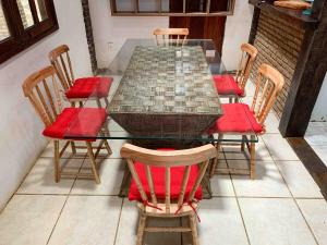 een eettafel met stoelen en rode stoelen bij Casa Baleia in Itacaré