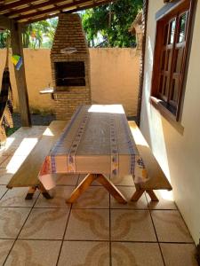 een houten tafel op een terras met een steenoven bij Casa Baleia in Itacaré