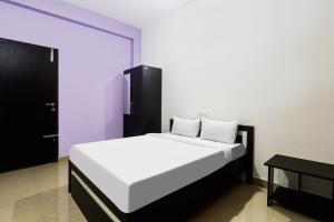 BelagulaHotel O MK Arcade的卧室配有白色的床和黑色橱柜。