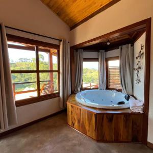 een grote badkamer met een groot bad en ramen bij Chalés Água azul in Santo Antônio do Pinhal
