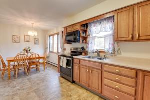 a kitchen with wooden cabinets and a table and a dining room at 15 Mi to Cochrans Ski Area Cozy Home with Yard! in Essex Junction