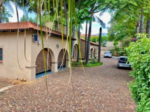 a house with a brick driveway next to a building at Kloofyard Guesthouse in Pretoria