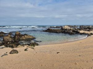 a sandy beach with rocks and the ocean at Condominio Parque Mar El Tabo in El Tabo