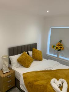 a bedroom with a bed with yellow pillows and a vase of flowers at Cosy Home Cardiff in Cardiff