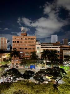a building with trees in front of a city at Hotel Plaza Mayor 44 in Medellín