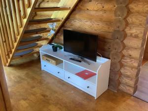 een tv op een witte kast in een kamer met een trap bij Blockhaus in Burhave in Hoddersdeich