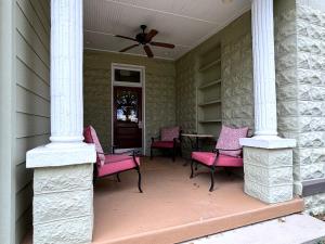 a porch with pink chairs and a ceiling fan at The Grand Lux Inn in Tullahoma