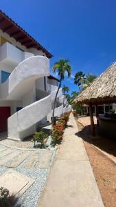 einen Fußweg neben einem weißen Gebäude mit Palmen in der Unterkunft Vida Playa el Agua in La Mira